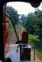 In den Anfangsjahren meiner Eisenbahnfotografie hatte ich nur selten die Möglichkeit zur Mitfahrt im Führerraum. Entsprechend wenige Fotos finden sich in meinem Archiv. Auf Anfrage nahm mich am 2.7.1986 das Lokpersonal der 323 176 mit auf der 8 Kilometer langen Kleinbahn Lohne – Dinklage. Dabei machte ich auch ein Foto aus dem Führerstandsfenster auf die Strecke.
